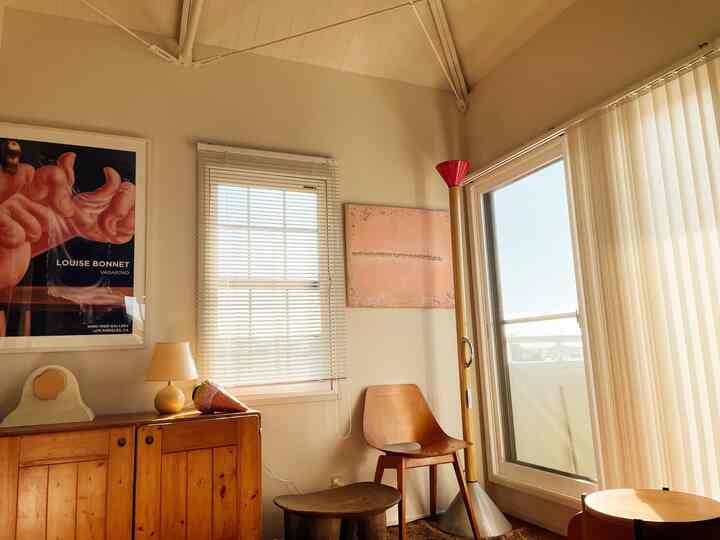 明るいホワイトの壁と木目調家具が配置されたヴィンテージのリビング、窓から暖かい日差しが差し込む雰囲気のある空間