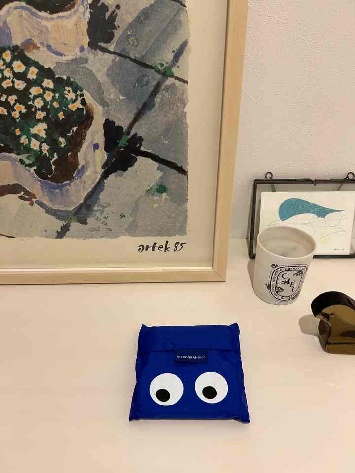 ブルーのエコバッグが置かれた、シンプルでミニマルな玄関の小物配置空間