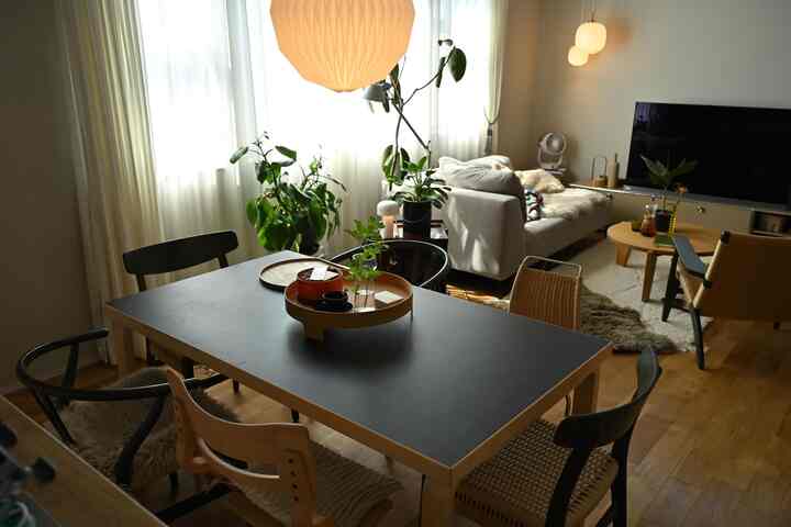 Natural color and white toned dining and living room featuring dining table with chairs and sofa in a cozy setting.