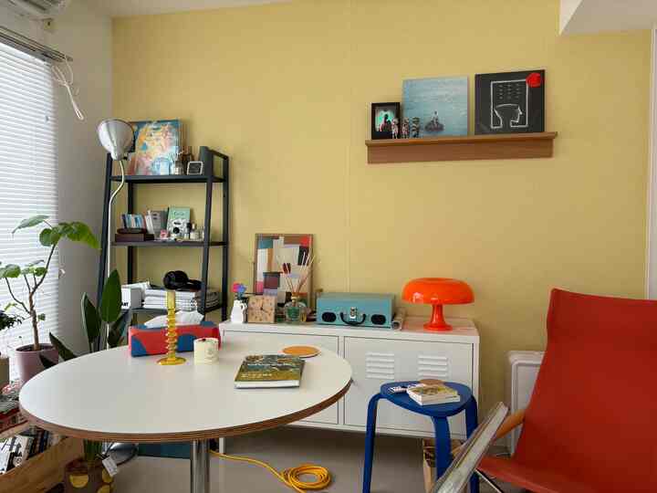 Yellow-toned wall and white round table with various decor and shelves in a natural living room