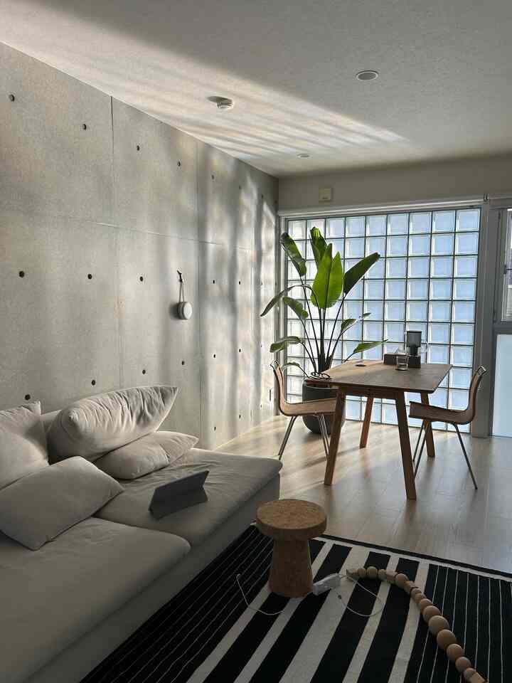 明るいホワイトと木目調が調和したリビングダイニング空間、コルクスツールと大きな植物が自然な印象を与えるシンプルモダンなインテリア