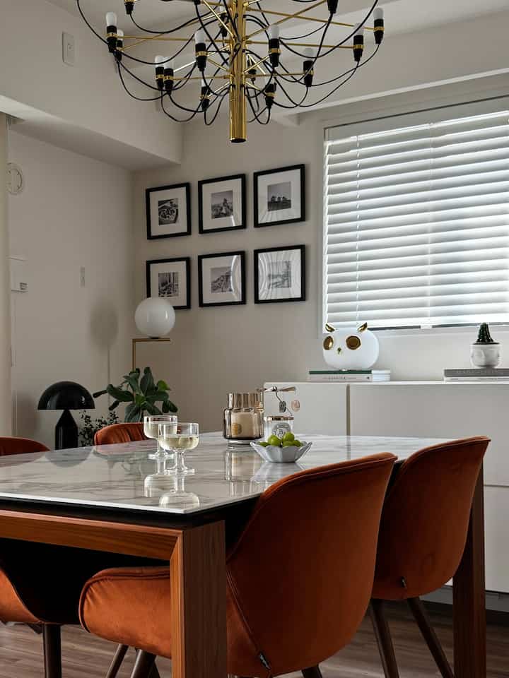 White and brown toned dining room featuring large marble dining table and orange velvet chairs, creating sophisticated atmosphere