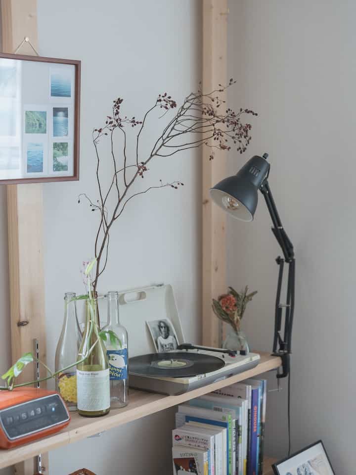 Natural color toned single household desk area featuring a record player, bookshelf, and desk lamp creating a cozy atmosphere