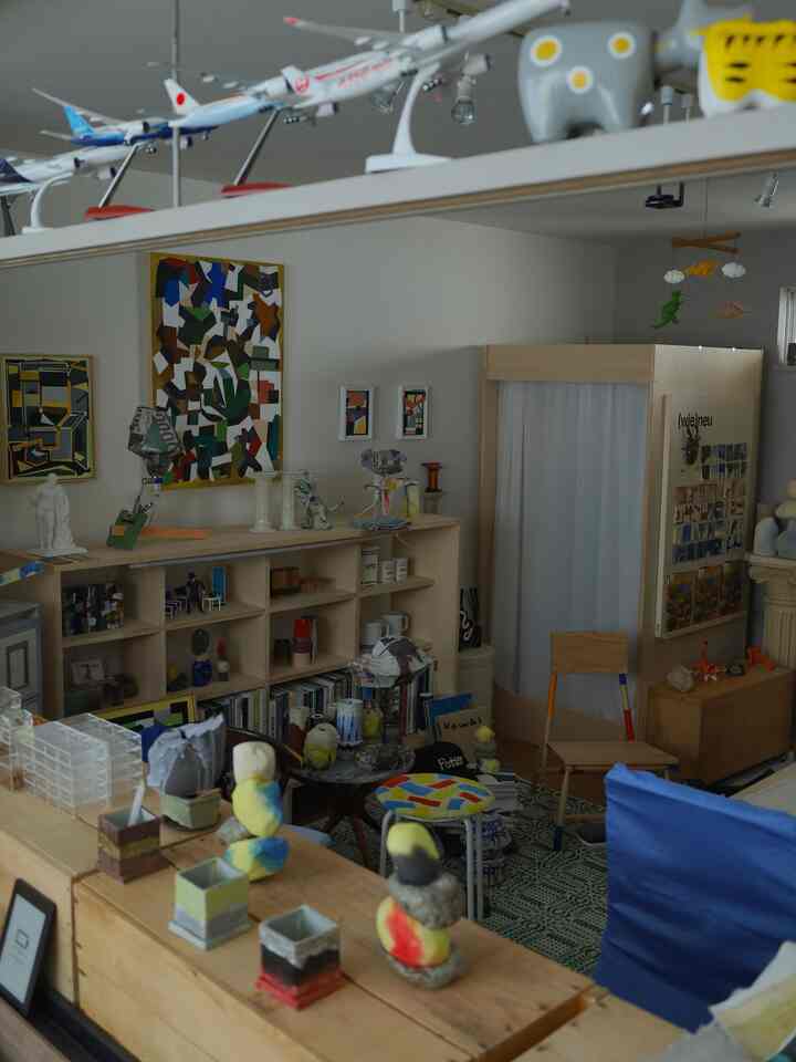 ナチュラルトーンの1LDKリビング、様々なアート作品と本棚が配置された雰囲気のあるインテリア