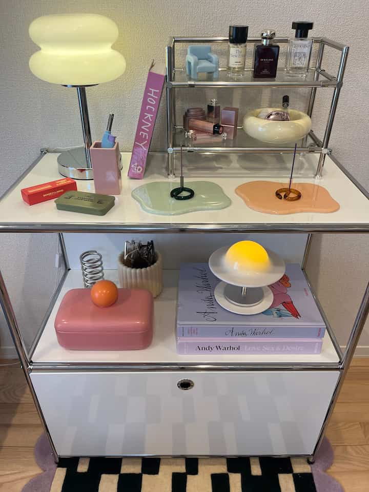 Mid-century modern style bedroom table with pink and white dominant colors featuring objets and table lamp
