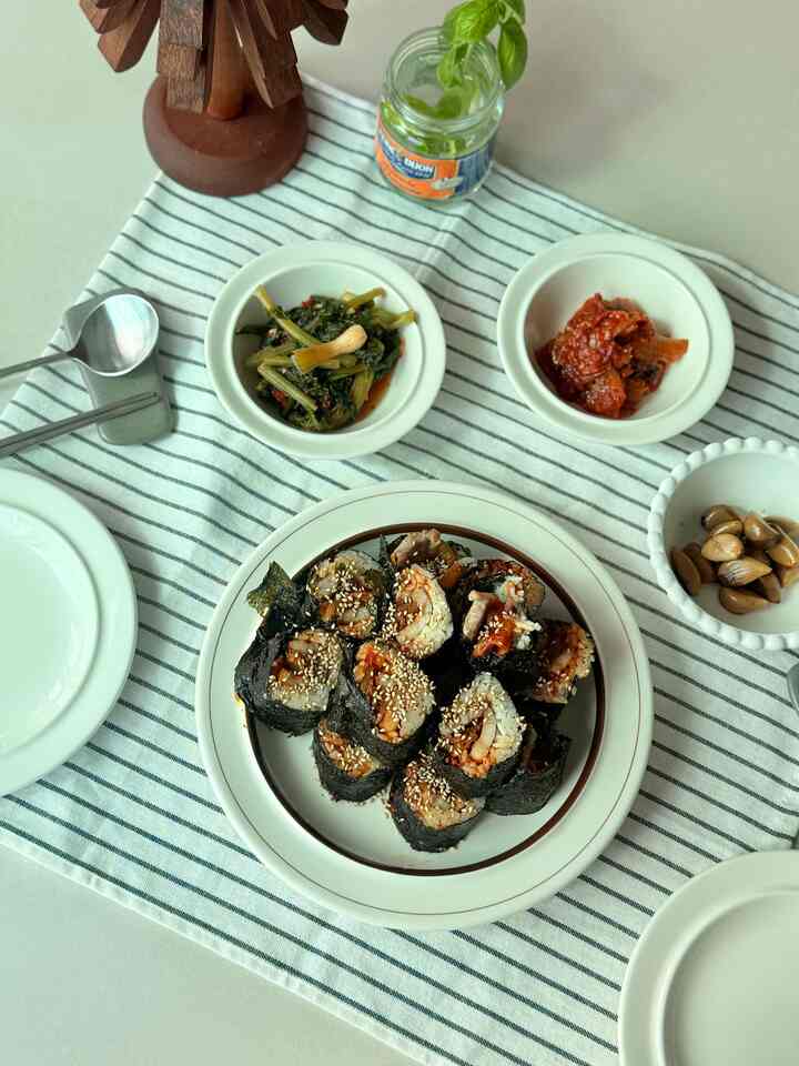 白を基調としたキッチンダイニングテーブルにキンパと副菜が並ぶ、温かみのある二人暮らしの食事風景