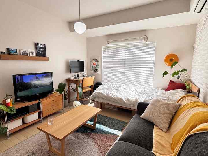 White-walled 1K single household bedroom and living space with wood-tone furniture and natural accents