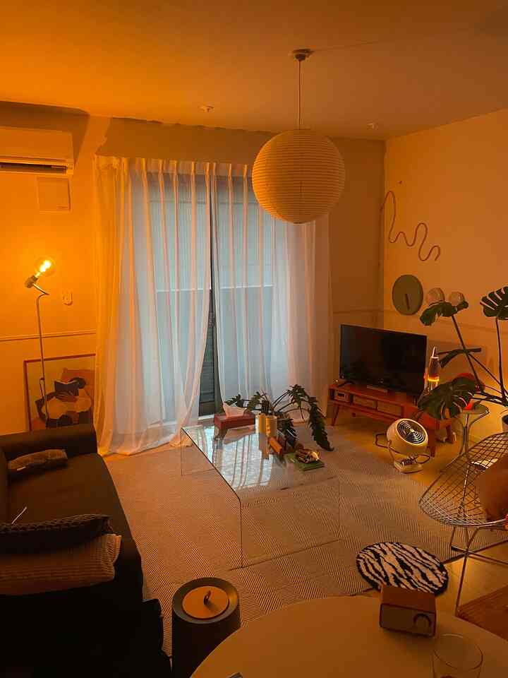 温かいオレンジ色の照明とミッドセンチュリーモダン家具が配置された居心地の良いリビングルーム