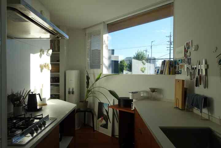 白と木目調のキッチン、大きな窓と調理器具が配置された雰囲気のあるインテリア