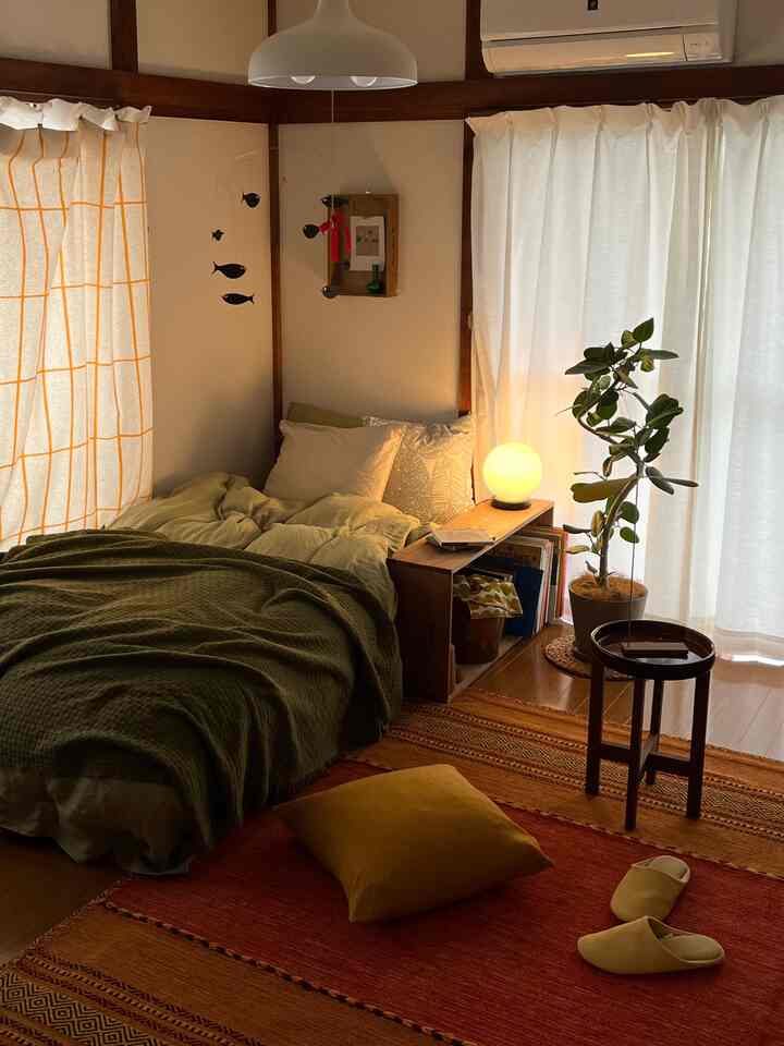 ナチュラルモダンな寝室、緑のブランケットとラグ、植物が配置され温かみのある雰囲気のある空間