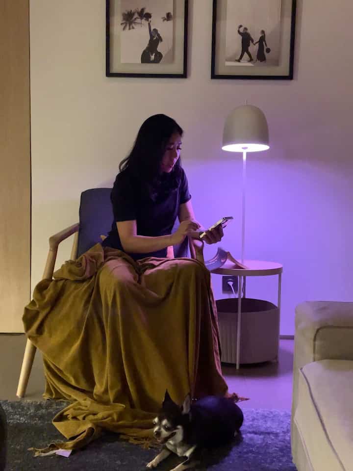 Natural tone living room featuring brown blanket, cream sofa, and purple-lit floor lamp creating cozy atmosphere