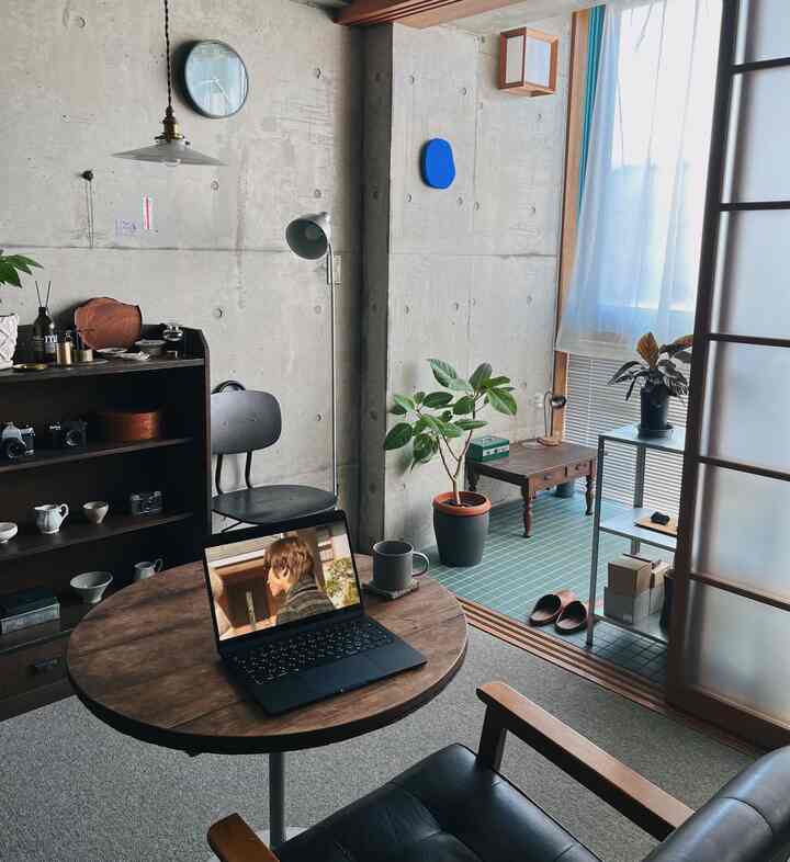 Gray-toned industrial living room featuring a wooden round table, black chairs, and plants creating a cozy atmosphere