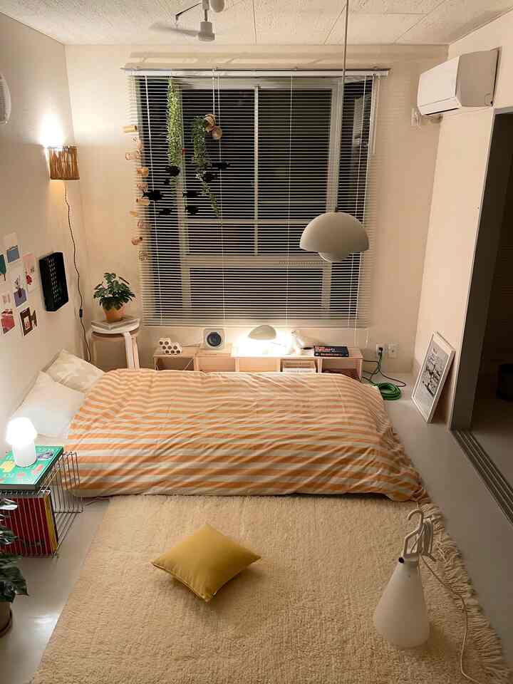 ベージュと白の色調の寝室、大きな窓とペンダントライトが配置された雰囲気のある空間