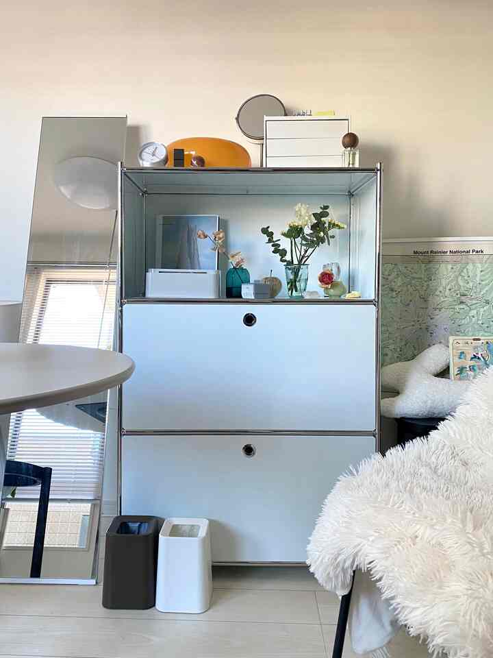 Bright white-toned studio featuring modular rack, full-length mirror, table and cozy chair in a clean modern interior