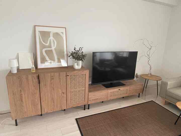 ナチュラルカラーと木目調家具が調和した北欧スタイルのリビング、アートポスターとテレビ台が配置された印象的な空間