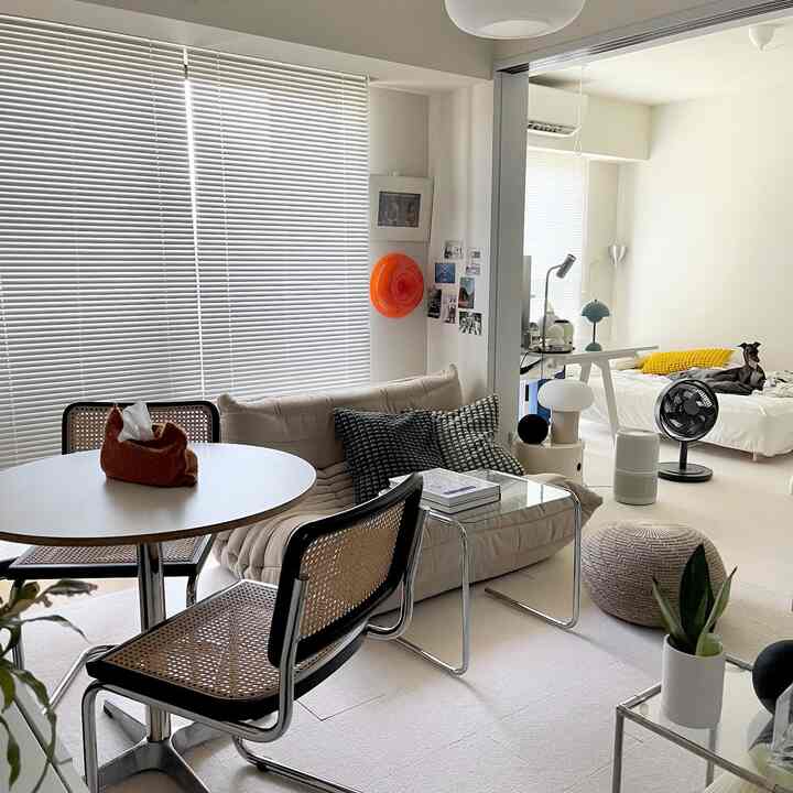 白とベージュのトーンが基調のワンルーム、ソファやダイニングテーブル、ベッドが配されたミニマルで清潔感のあるインテリア