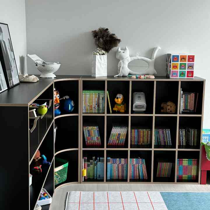 モノトーンの黒い本棚が配置された子供部屋の遊び空間、多様な絵本やおもちゃが整頓された印象的なインテリア