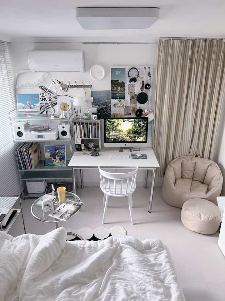 白とベージュのコンパクトな一人暮らしの部屋、清潔な白いデスクとiMac、ベージュのビーズクッションが配置されたミニマルなホームオフィス