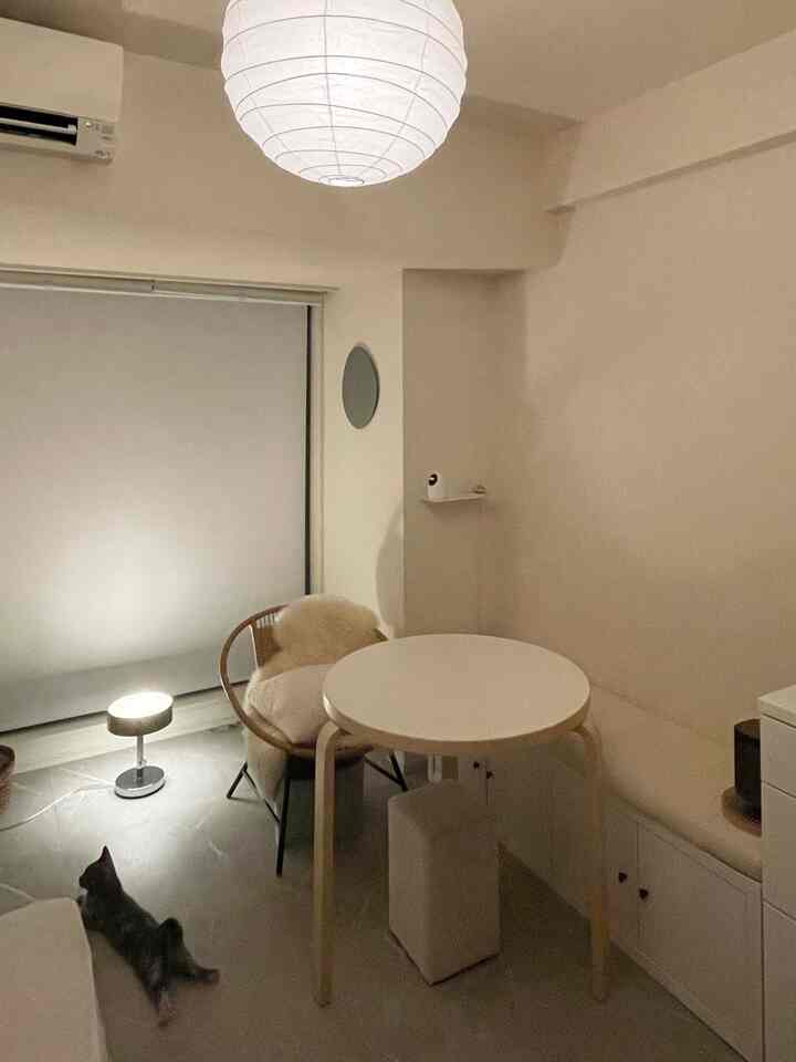 ホワイトとナチュラルな木目調が調和した小さなダイニング空間、ラウンドテーブルと快適なアームチェアが配置されたシンプルなインテリア