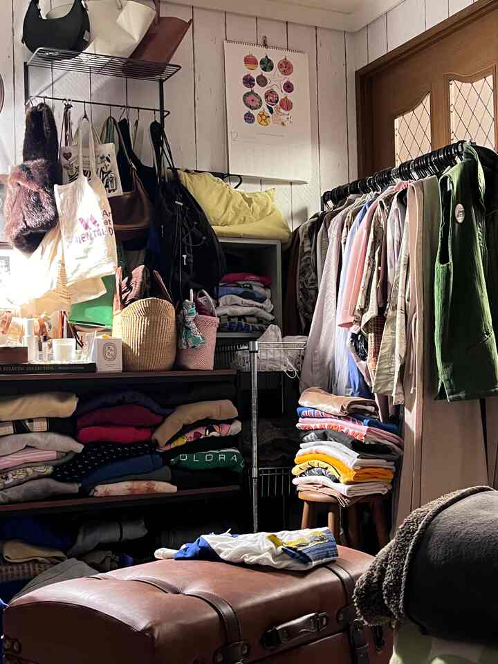 Brown-toned small dressing room with densely stored clothes and bags arranged in a compact area