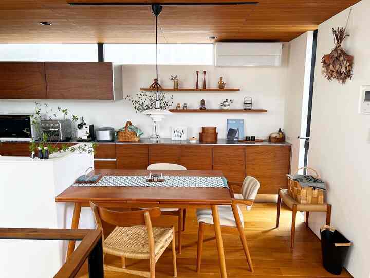 ナチュラルな木目調と白い壁が調和した二人暮らしのキッチンダイニング、ペンダントライトと収納棚が配置された温かみのある空間