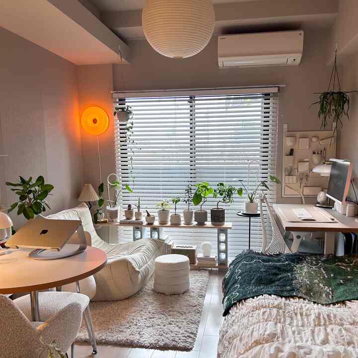 アイボリー調の家具と植物が配置された、自然で明るい雰囲気のホームオフィス兼リビングルーム