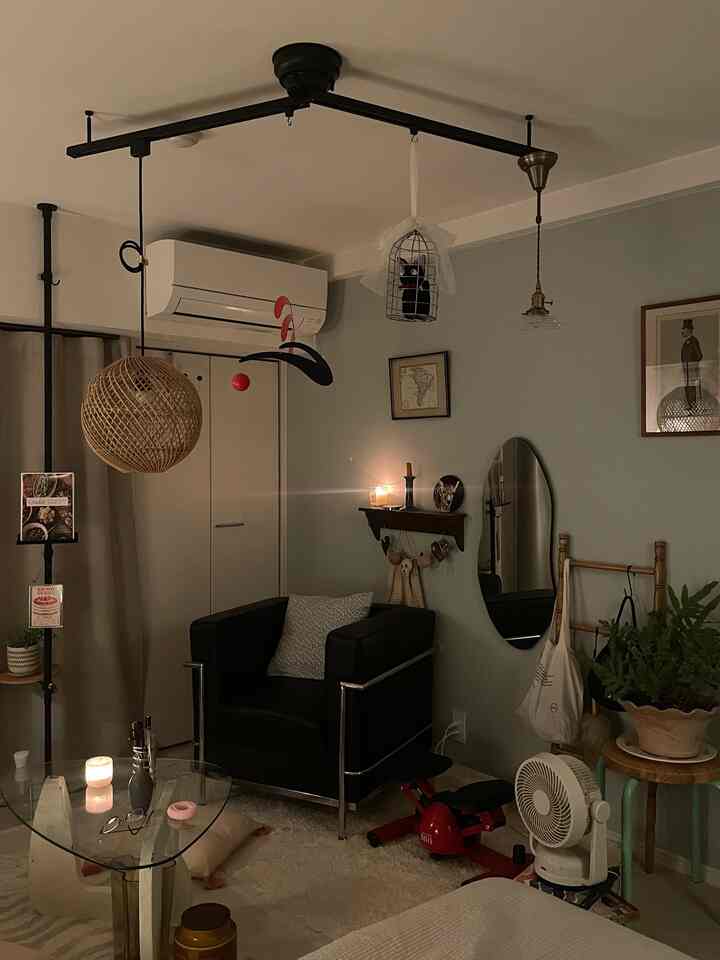 ブラックとナチュラルトーンが調和する1Kリビング、黒いアームチェアとガラステーブル、猫モチーフの小物が居心地の良い雰囲気を演出している