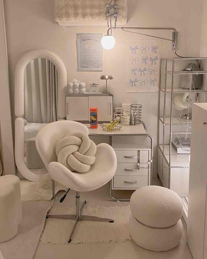 柔らかなホワイトトーンの狭い部屋、クロームの壁照明とメタルフレームのデスク＆ドレッサー、回転椅子とスツールが配置されたモダンな空間