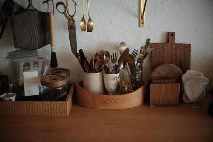 温かみのある木目調のキッチン、整理されたカトラリーと調理器具が配置された収納アイデアのあるインテリア