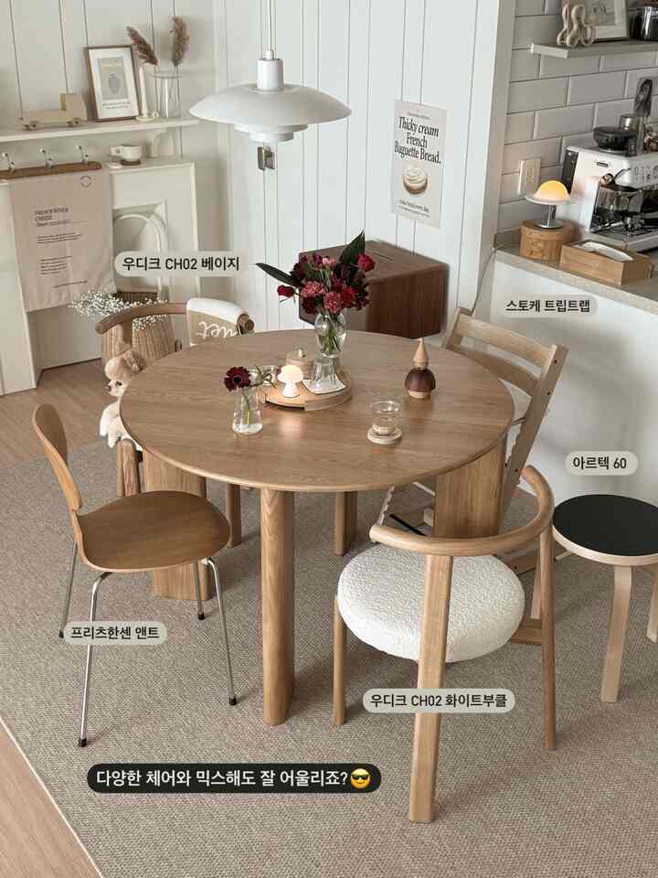 ナチュラルな木目調とベージュの色調が特徴の、様々な椅子が配置されたおうちカフェ風の円形ダイニングルーム