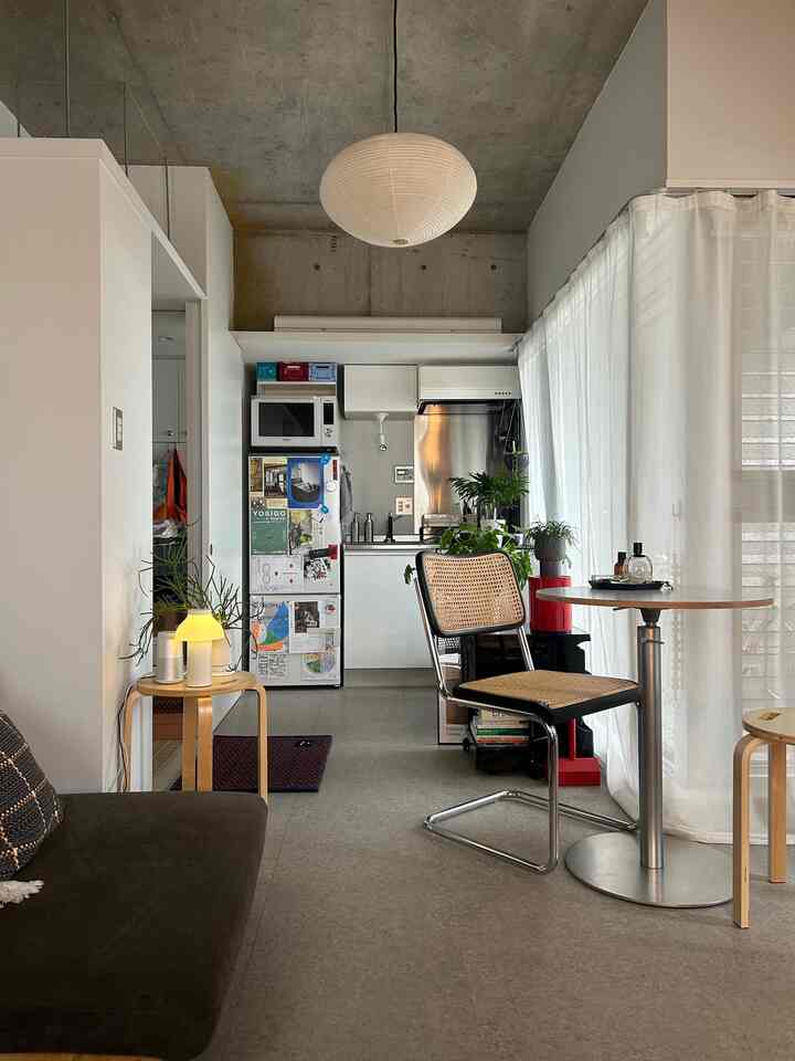 Natural wood furniture and white walls under a gray concrete ceiling in a studio apartment living room and kitchen space