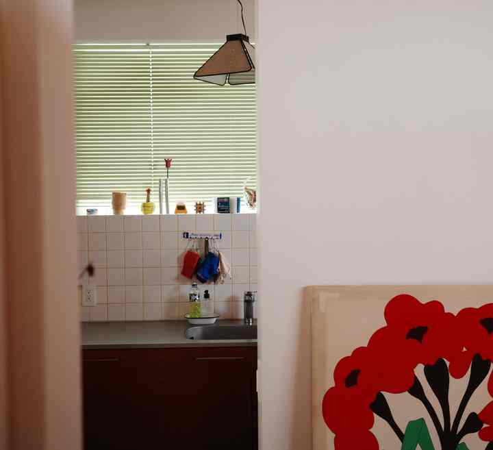 白と茶色の色調のキッチン、タイルの壁と緑のブラインド、ペンダントライトが調和する暖かみのあるインテリア