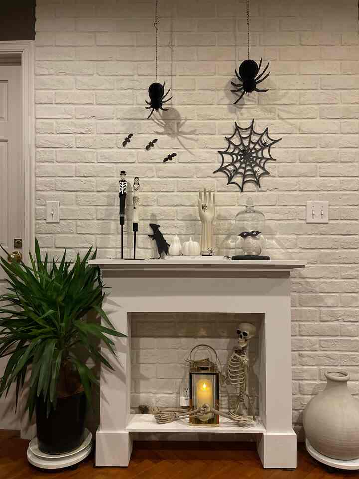 白いレンガの壁と黒いハロウィン飾りが配置されたリビングの暖炉のあるインテリア