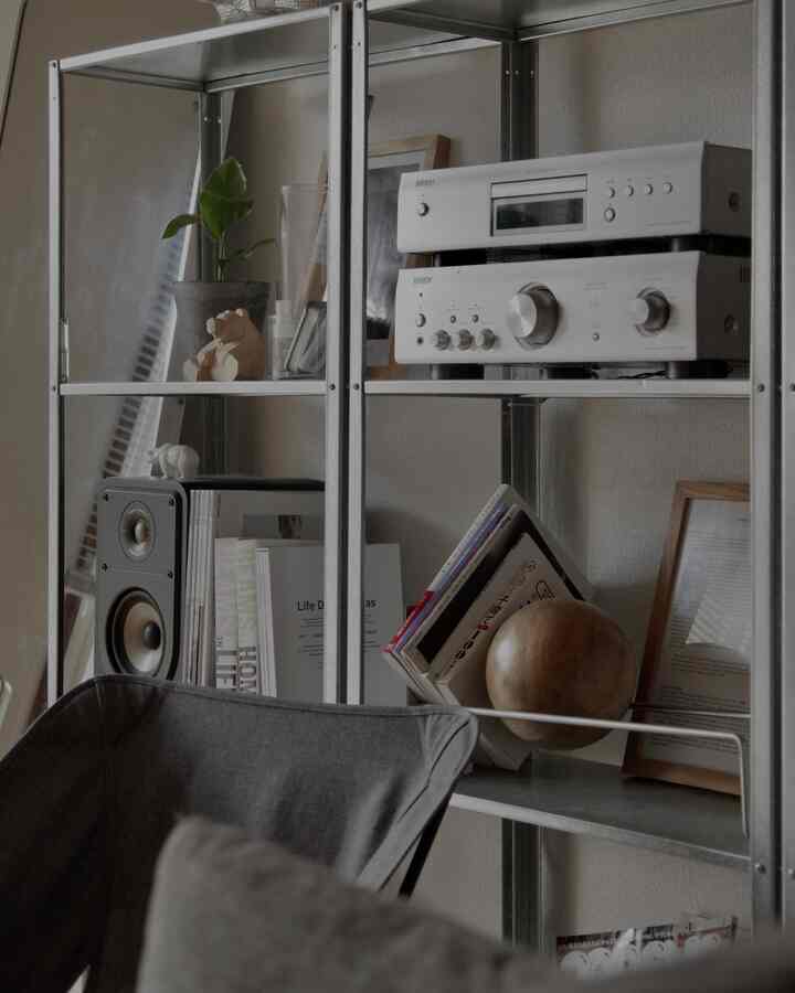 グレーのアウトドアチェアとメタルシェルフが配置されたモダンで北欧風のコンパクトな室内空間