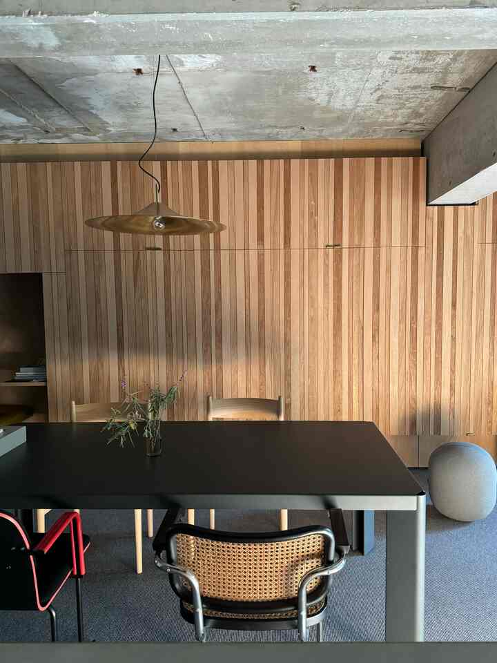 Wood tone wall and black dining table in a vintage-style dining room featuring a central pendant light
