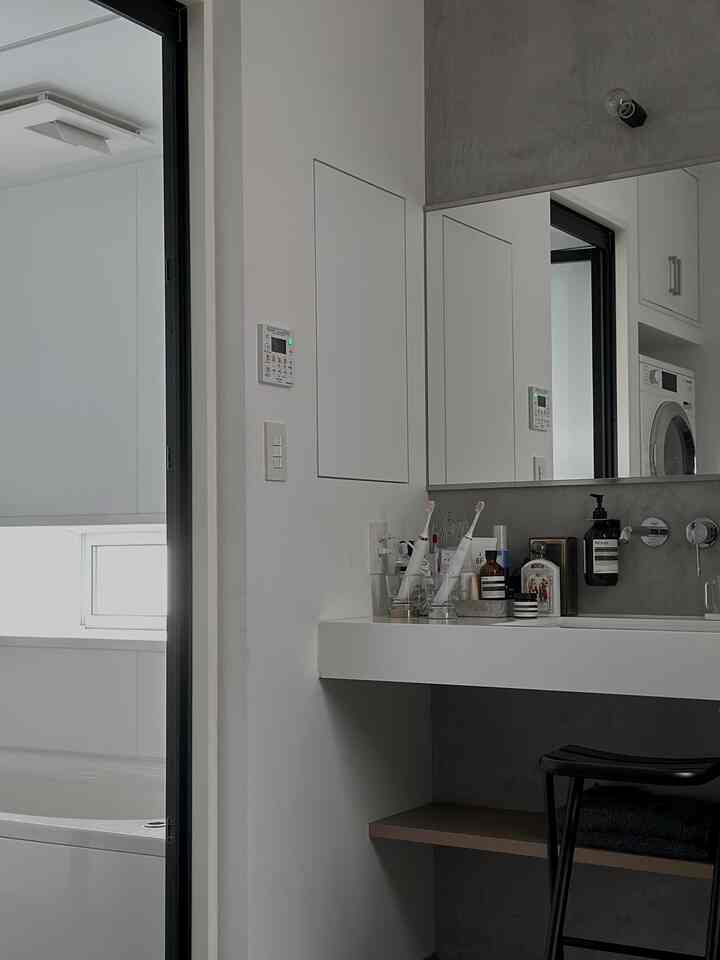 White and gray toned bathroom featuring a sink with mirror and partial view of a washing machine in a clean, minimal space