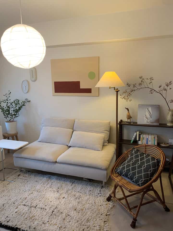 Natural tone living room featuring beige sofa, wooden floor lamp, rattan chair creating cozy interior
