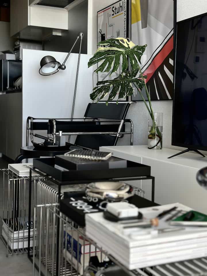 白と黒のトーンでまとめられたモダンなリビング、アームチェア、フロアランプ、サイドテーブルが配置されたシンプルな空間