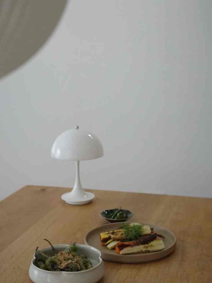 白い壁と木目調のダイニング、テーブルランプと料理が置かれた秋の食欲を感じる雰囲気のある空間