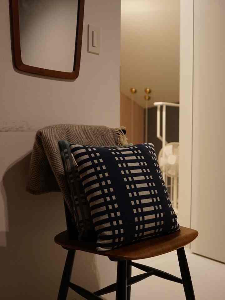 Cozy bedroom corner with Nordic style featuring a wooden armchair adorned with cushions and a blanket