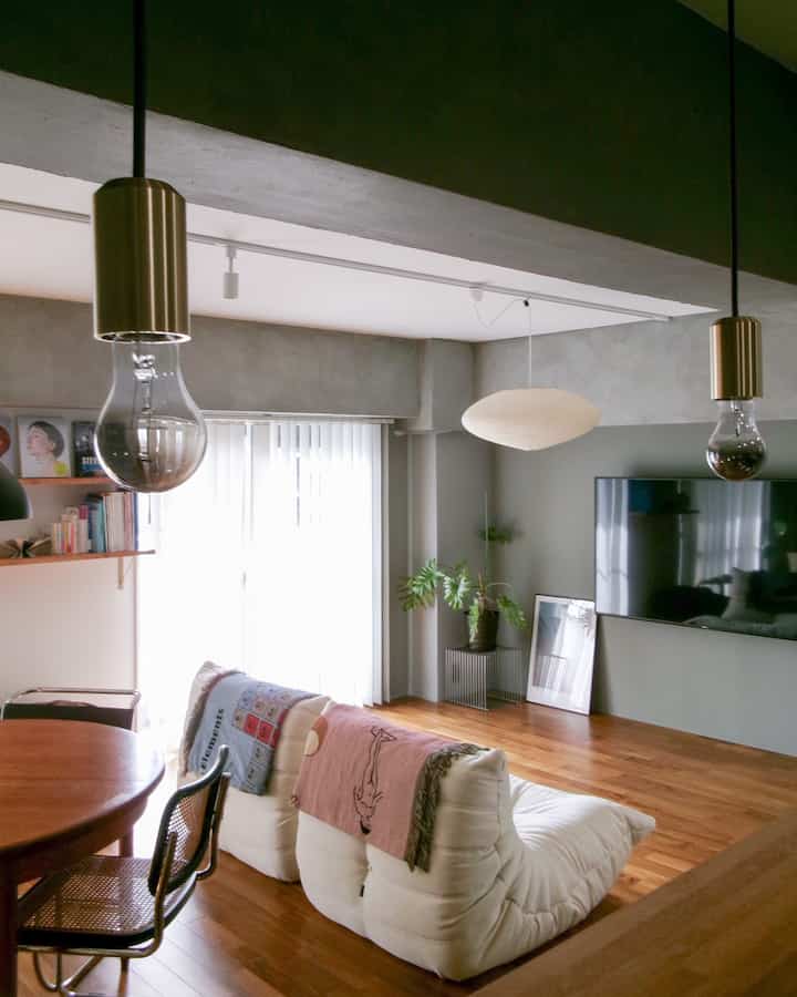 白と木目調のリビング・キッチン空間、モダンなミッドセンチュリーデザイン家具とペンダントライトが配置された雰囲気のあるインテリア