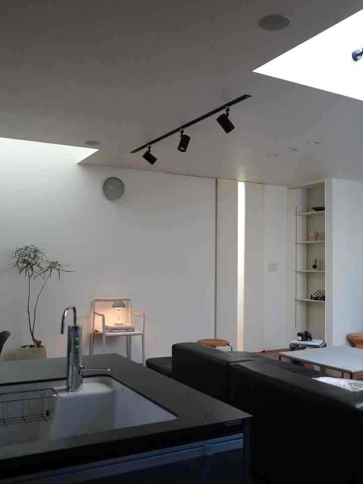 白と木目調の北欧スタイルのリビングとキッチン、モダンな家具と照明が配置された清潔でゆったりとした空間