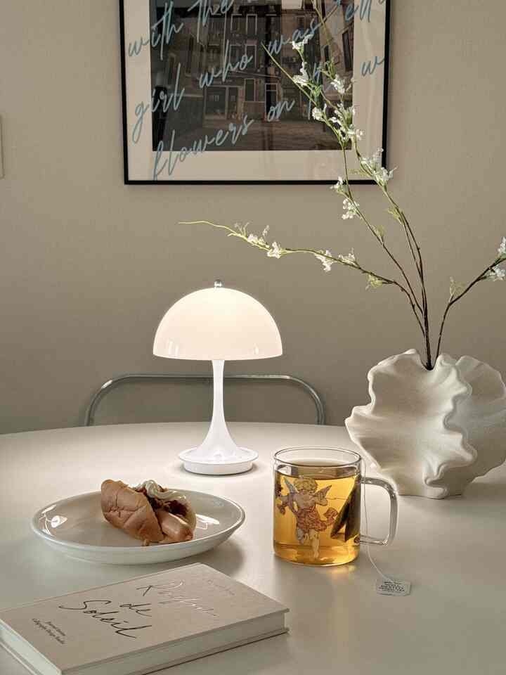 ベージュとホワイトの色調のキッチン空間、円形のダイニングテーブルに透明なグラスマグと暖かい照明が配されたシンプルで落ち着いた雰囲気のインテリア