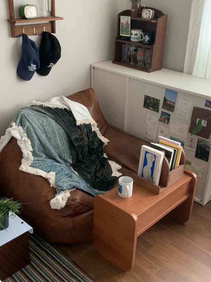 ダークブラウンのビーズクッションと木目調のサイドテーブルが配置された、小さくて雰囲気のあるナチュラルな空間