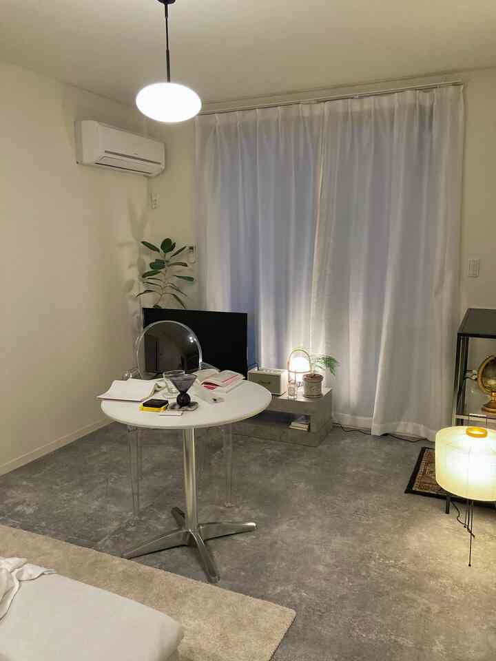 モノトーンでシンプルなリビング、中央に白い丸テーブルの勉強スペースと学習アイテムが配置された空間