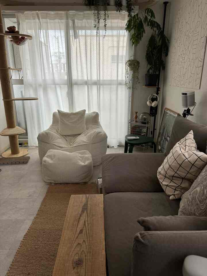 ナチュラルカラーのリビングルーム、白のビーズクッションとグレーのソファが配置された落ち着いた空間