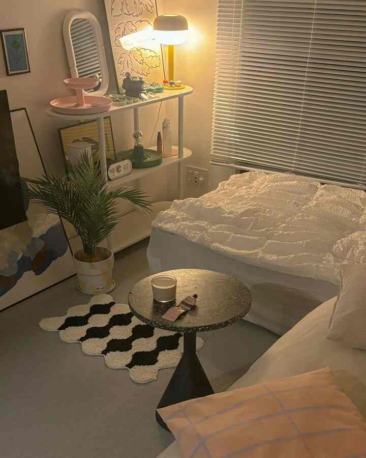Warm beige and white toned bedroom featuring side table and plant, styled with a calm nighttime atmosphere