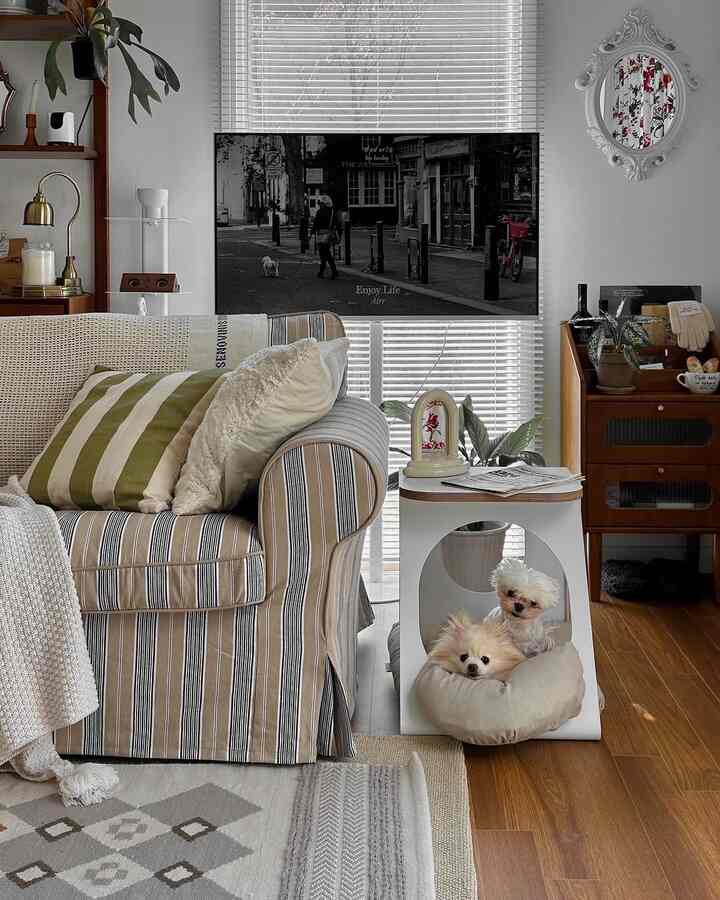 ウッドトーンとアイボリーの暖かいリビング、ストライプのソファとペットハウスに犬2匹がいる雰囲気のある空間