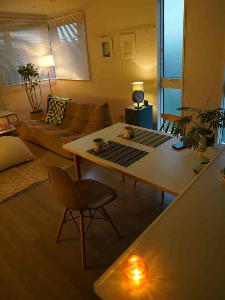 Natural tone living room featuring beige sofa and white dining table with warm, cozy mood lighting