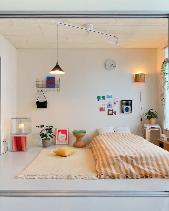 Bright white and natural-toned bedroom featuring striped duvet cover and wooden stool with cozy ambiance
